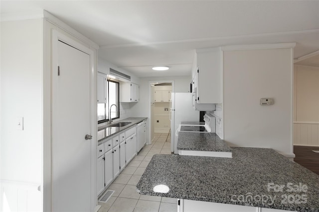 kitchen featuring white cabinets, visible vents, white appliances, a sink, and light tile patterned floors