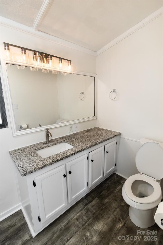 bathroom with baseboards, crown molding, wood finished floors, and vanity