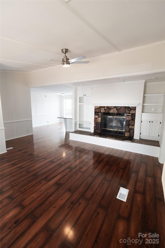 unfurnished living room with visible vents, wood finished floors, ceiling fan, and a decorative wall