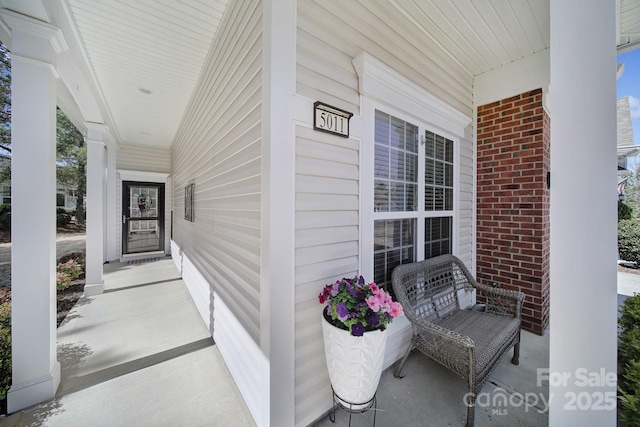 view of exterior entry with brick siding and a porch