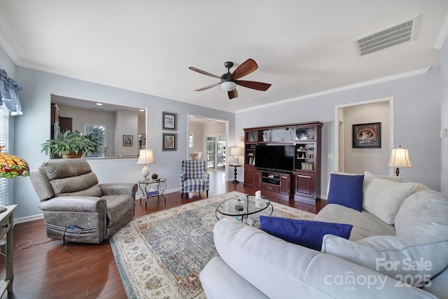 living area featuring baseboards, a ceiling fan, crown molding, dark wood-type flooring, and visible vents