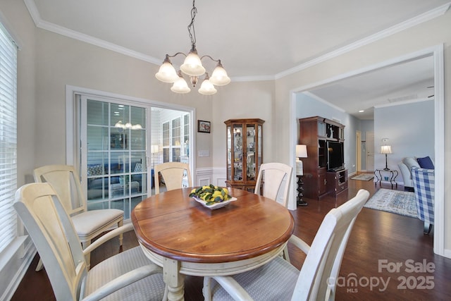 dining area with ornamental molding, a wainscoted wall, a notable chandelier, and wood finished floors