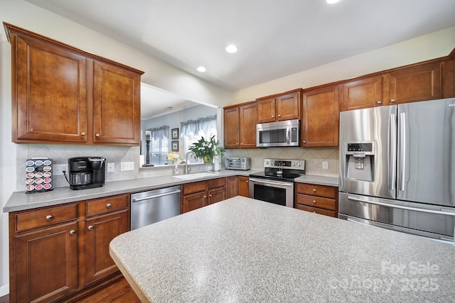 kitchen featuring tasteful backsplash, brown cabinets, a sink, and stainless steel appliances
