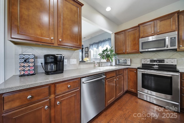 kitchen featuring a sink, tasteful backsplash, dark wood-style flooring, and stainless steel appliances