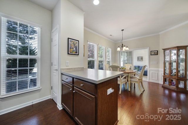 kitchen with light countertops, a peninsula, a notable chandelier, and dark wood-style floors