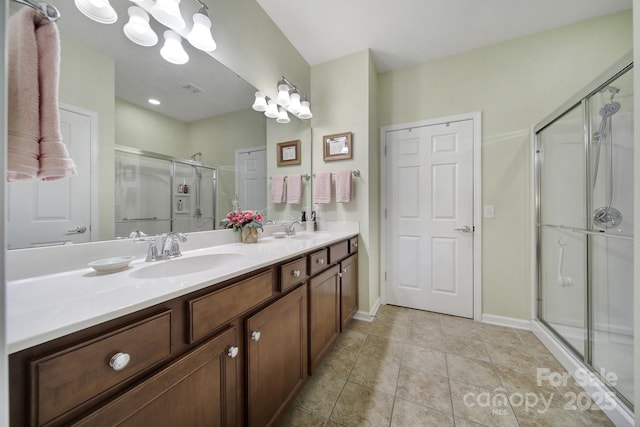 full bathroom featuring a stall shower, double vanity, a sink, and tile patterned floors