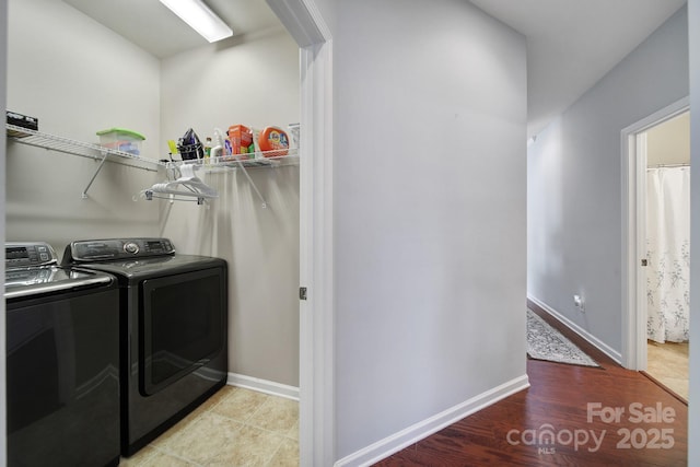 clothes washing area featuring laundry area, light wood finished floors, baseboards, and washing machine and dryer