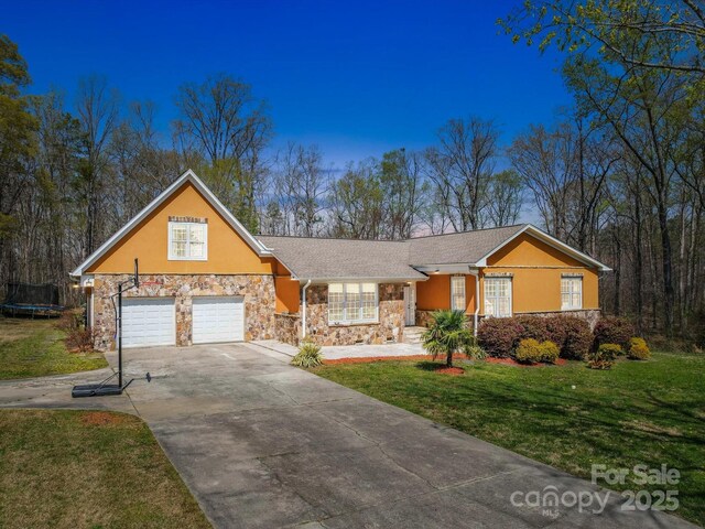 605 Allen Way, Indian Trail, NC 28079 - view of front of house featuring stone siding, a trampoline, driveway, a front lawn, and stucco siding