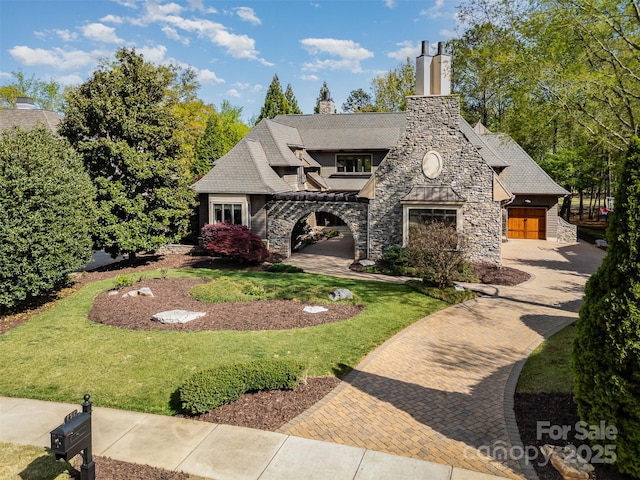 view of front facade featuring a chimney, stone siding, and a front lawn