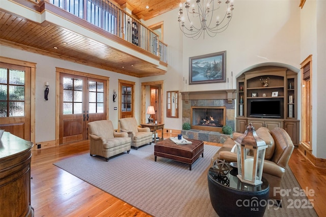 living room featuring an inviting chandelier, wood ceiling, wood finished floors, french doors, and a high end fireplace