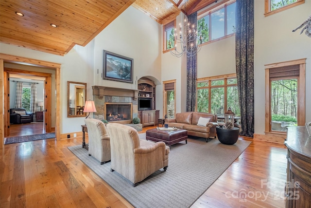 living room with baseboards, hardwood / wood-style floors, a stone fireplace, and wooden ceiling