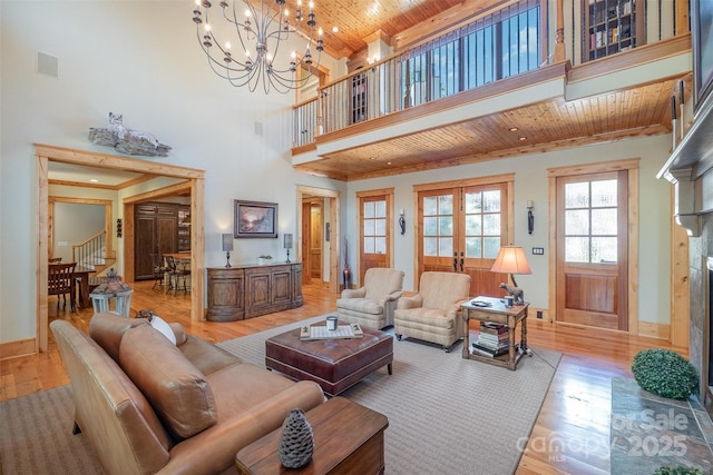 living area with light wood-type flooring, a chandelier, wooden ceiling, stairs, and french doors