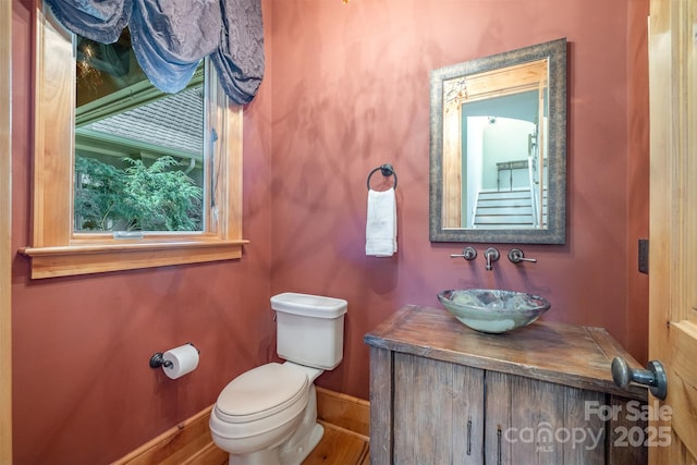 half bathroom featuring toilet, vanity, and baseboards