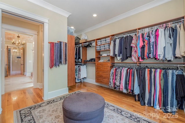 spacious closet with a notable chandelier and wood finished floors