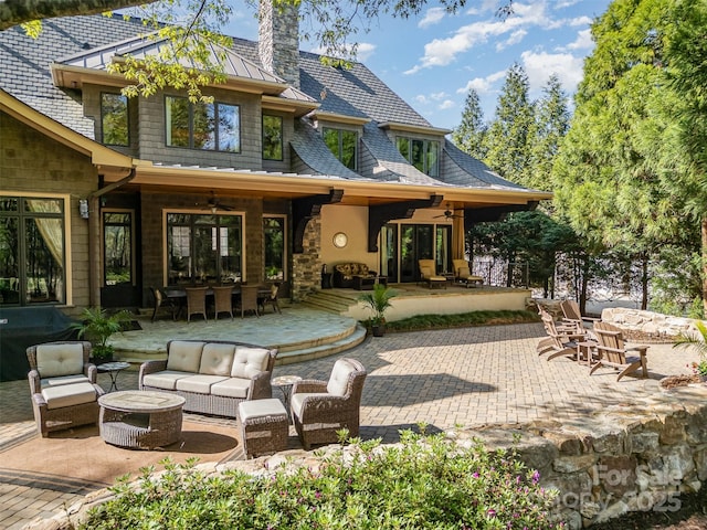 rear view of property featuring an outdoor living space with a fire pit, ceiling fan, a patio, a chimney, and outdoor dining space