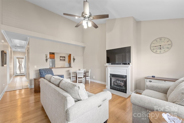 2783 Clover Rd NW, Concord, NC 28027 - living room with attic access, ceiling fan, light wood-style flooring, a towering ceiling, and a fireplace with flush hearth