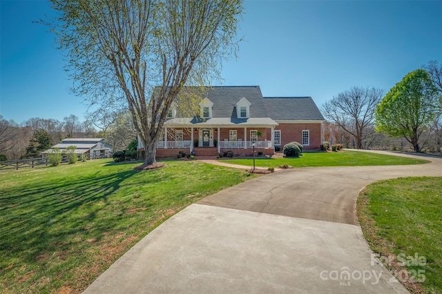 cape cod home featuring a front yard, covered porch, brick siding, and curved driveway