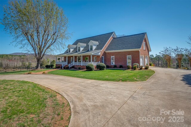 view of front of home featuring covered porch, brick siding, driveway, and a front lawn