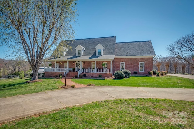 cape cod-style house featuring a front lawn, a porch, and brick siding