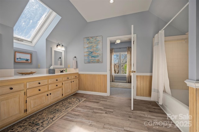 full bath featuring lofted ceiling with skylight, a wainscoted wall, shower / bath combo, and wood finished floors