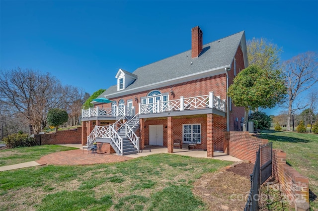 rear view of house featuring brick siding, stairway, a yard, and a patio area