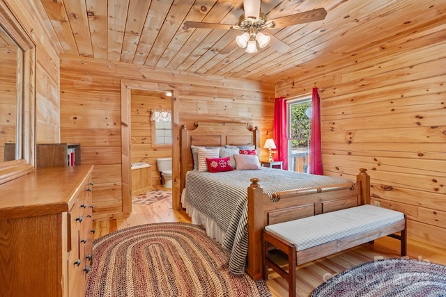 bedroom with ensuite bathroom, wood finished floors, wood ceiling, and wood walls