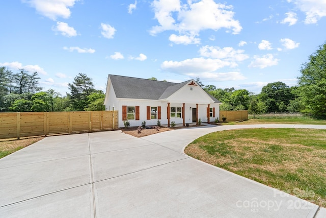 modern farmhouse featuring curved driveway, fence, and a front yard
