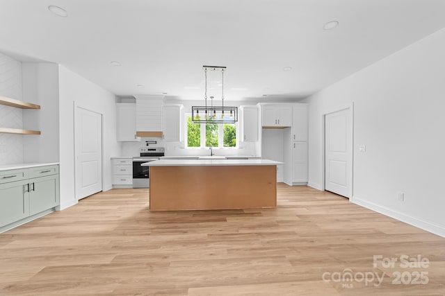 kitchen featuring a center island, electric stove, white cabinets, and light countertops