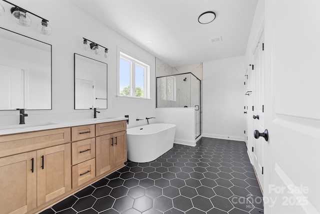 full bathroom featuring a freestanding bath, a sink, tile patterned flooring, double vanity, and a stall shower