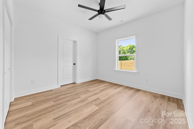 spare room featuring baseboards, ceiling fan, light wood-style flooring, and visible vents