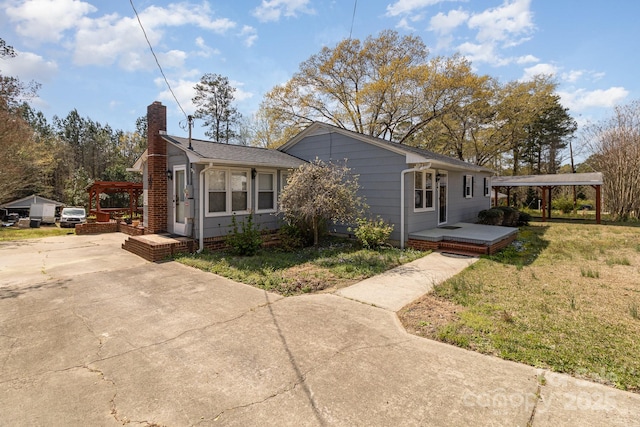 view of front of house featuring driveway, a chimney, and a front lawn
