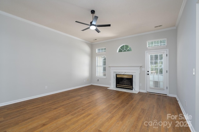 unfurnished living room with plenty of natural light, visible vents, a premium fireplace, and a ceiling fan