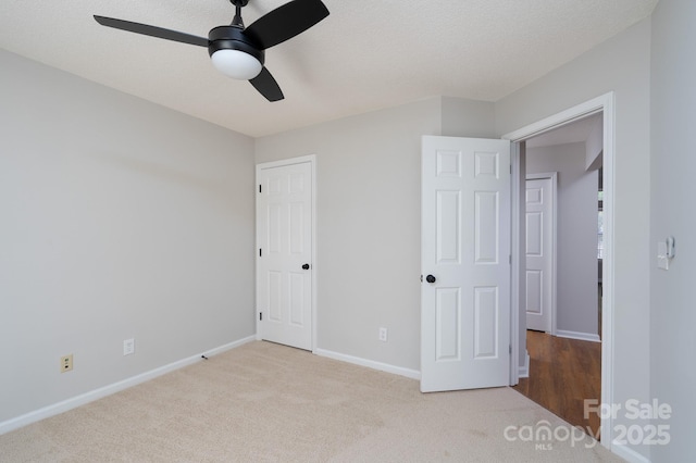 unfurnished bedroom with baseboards, a textured ceiling, a ceiling fan, and carpet