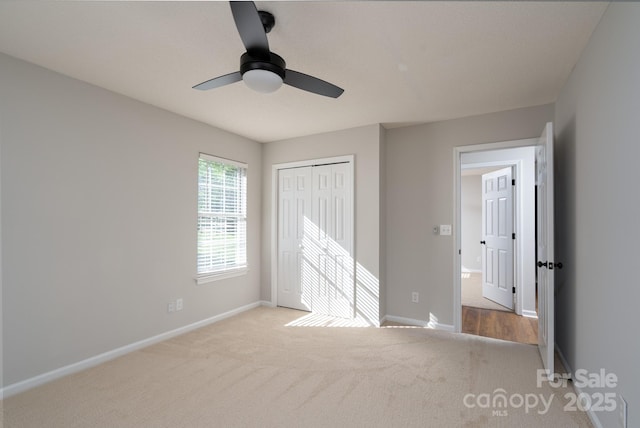 unfurnished bedroom featuring a closet, carpet flooring, baseboards, and a ceiling fan