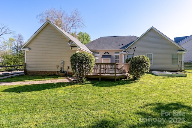 rear view of house featuring a wooden deck and a lawn