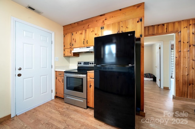 kitchen with stainless steel range with electric stovetop, visible vents, under cabinet range hood, light wood-style floors, and freestanding refrigerator