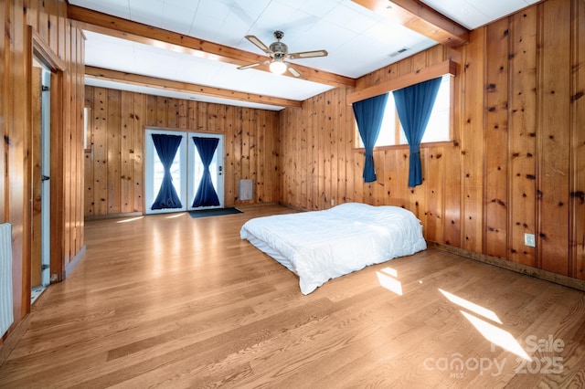unfurnished bedroom featuring beam ceiling, multiple windows, and wood finished floors