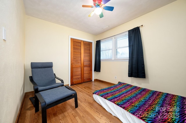 bedroom with baseboards, a closet, light wood-style floors, and ceiling fan