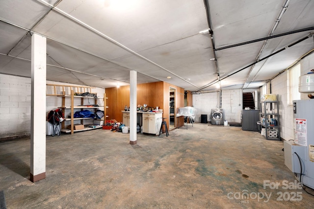 finished basement with electric water heater, concrete block wall, and washer / dryer