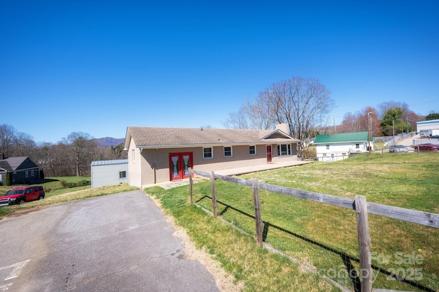 ranch-style home with a front yard, fence, french doors, and aphalt driveway
