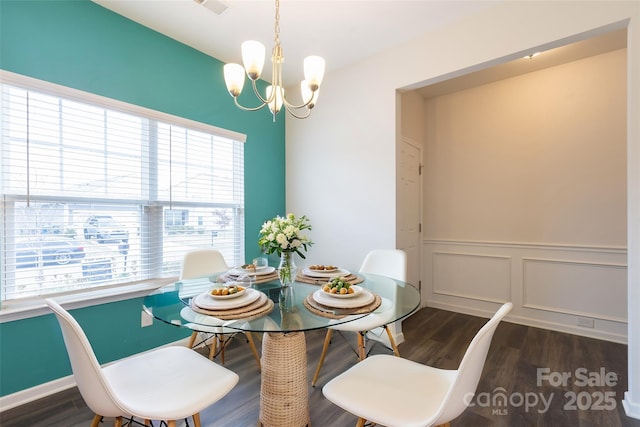 dining room with a decorative wall, a wainscoted wall, a notable chandelier, and wood finished floors