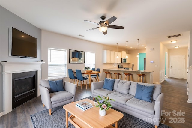 living area featuring a ceiling fan, dark wood-style flooring, and visible vents