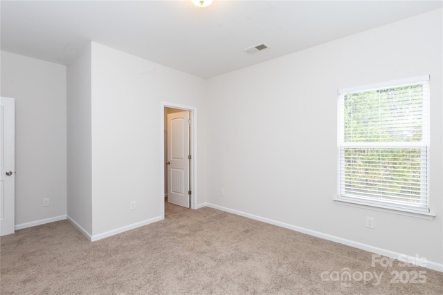 spare room with baseboards, visible vents, and carpet