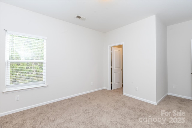 carpeted spare room featuring baseboards and visible vents