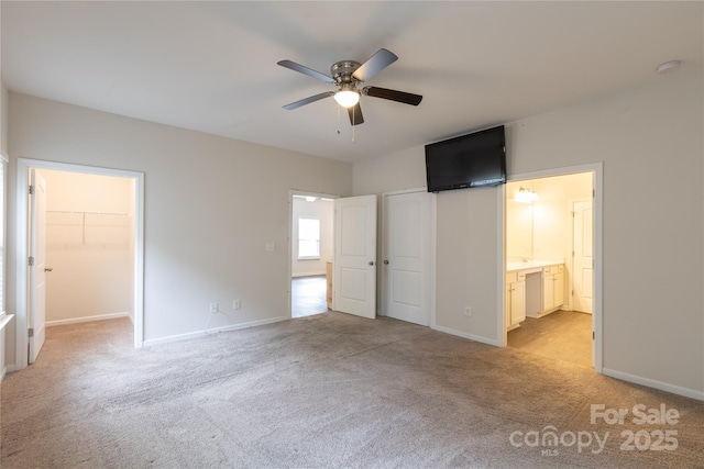 unfurnished bedroom featuring ensuite bathroom, carpet floors, baseboards, and a walk in closet