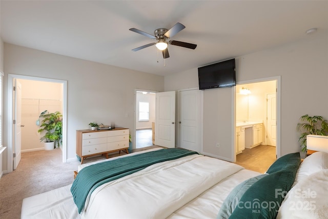 bedroom featuring baseboards, ensuite bath, a ceiling fan, and light carpet