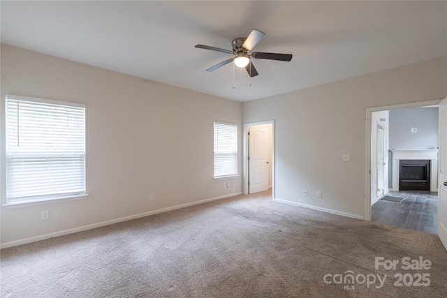 empty room with baseboards, carpet flooring, ceiling fan, and a fireplace