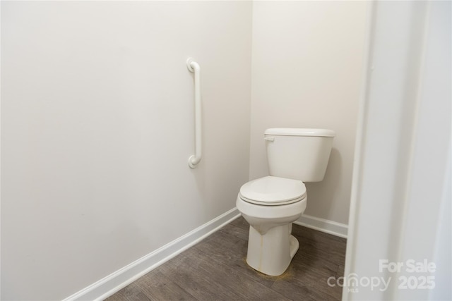 bathroom featuring baseboards, wood finished floors, and toilet