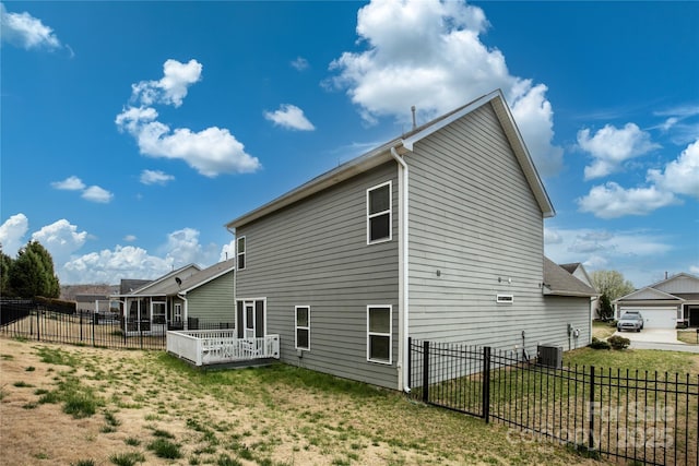 back of house featuring central air condition unit, fence, and a yard
