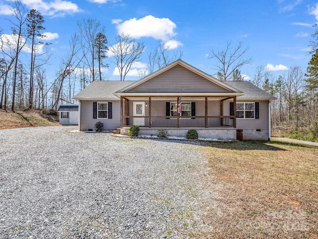 view of front of home with covered porch, roof with shingles, a front lawn, gravel driveway, and crawl space